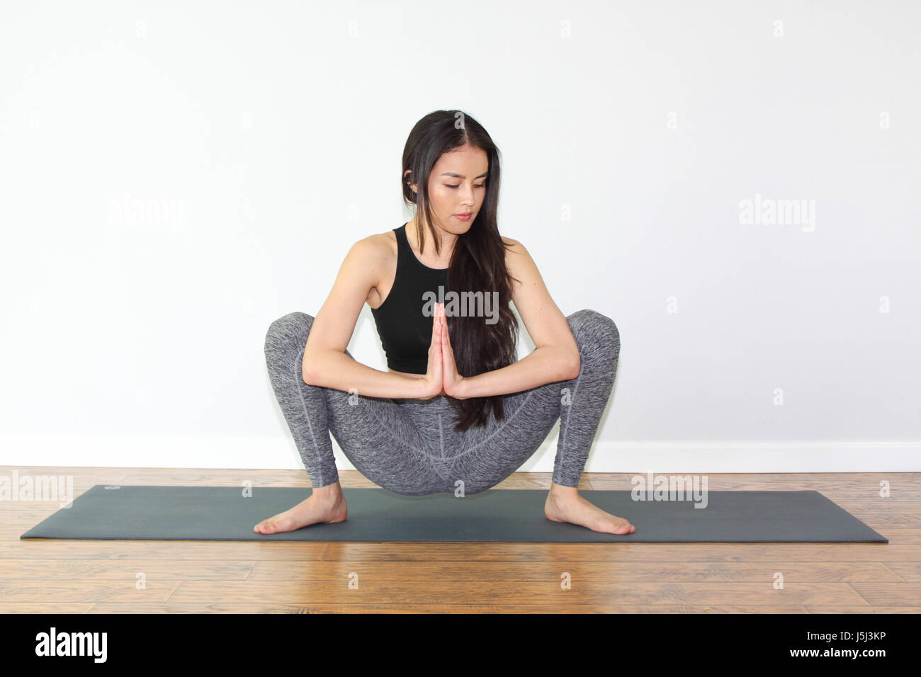 Bella donna facendo un po' di yoga pongono chiamato squat pongono, o malasana pongono. Foto Stock