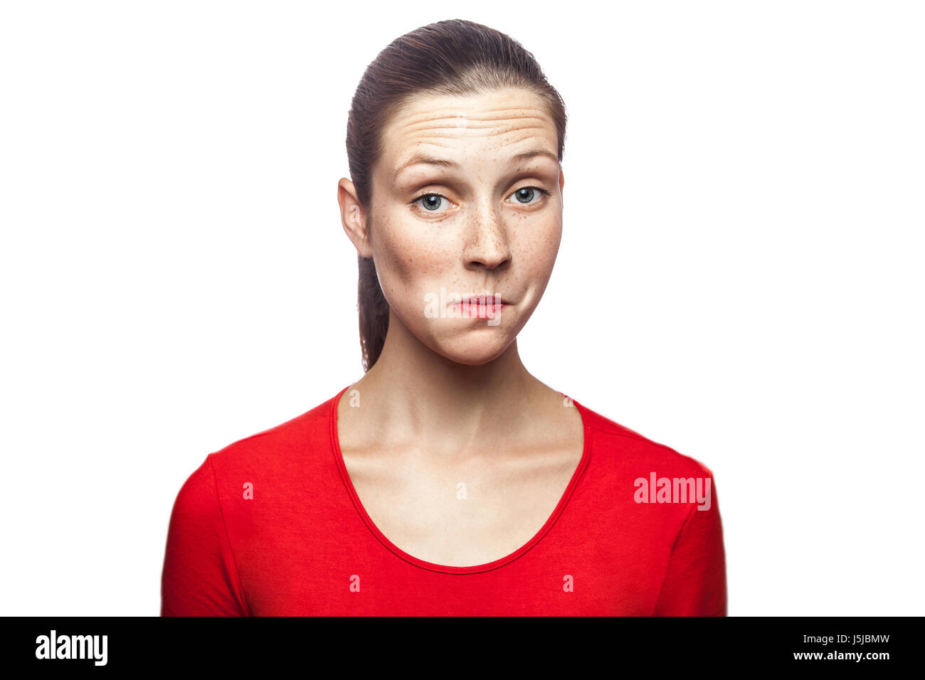 Non so. ritratto di funny confuso woman in red t-shirt con lentiggini. guardando la telecamera, studio shot. isolato su sfondo bianco. Foto Stock