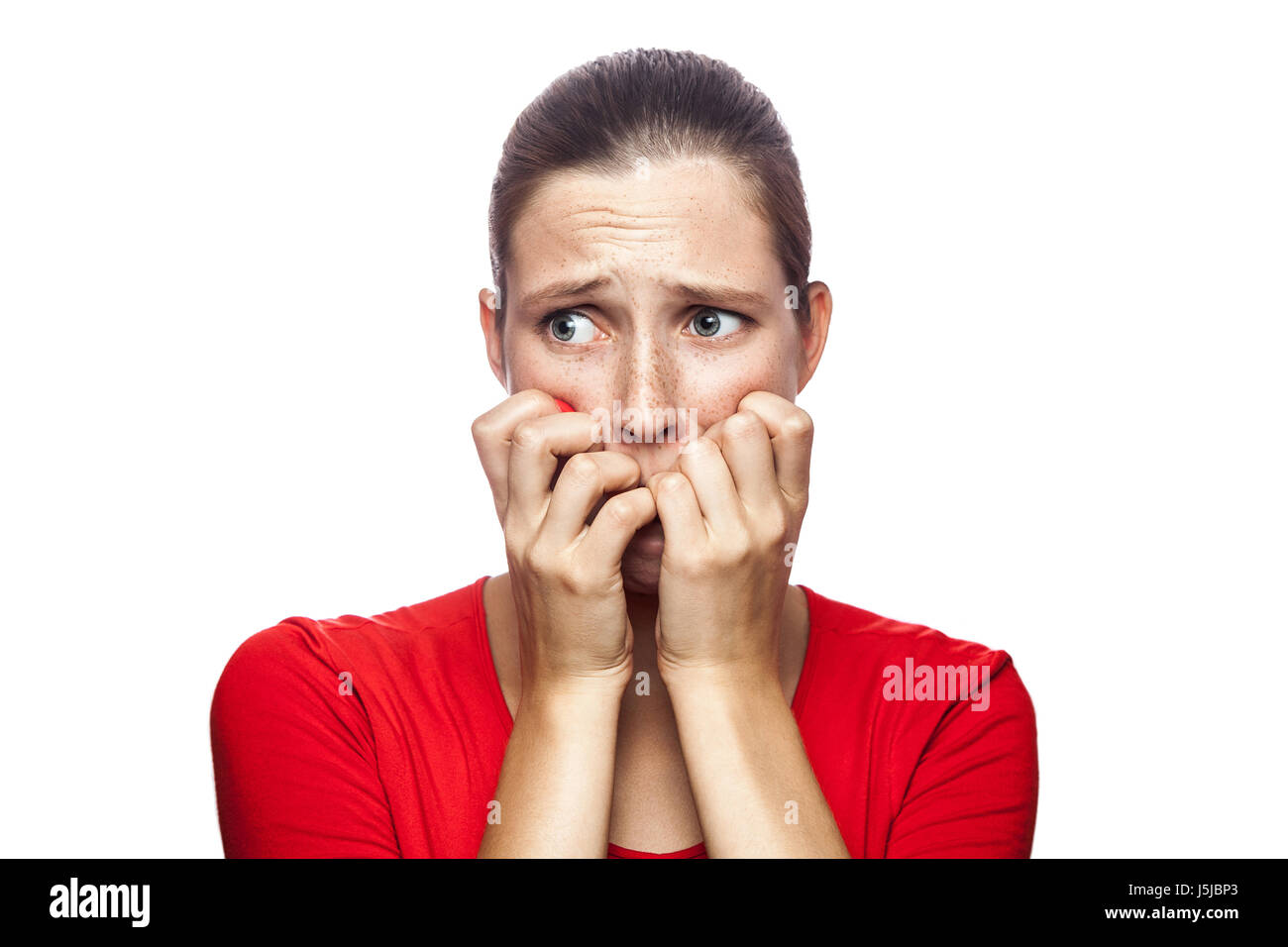 Ritratto di preoccupato scared woman in red t-shirt con lentiggini. guardando la telecamera, studio shot. isolato su sfondo bianco. Foto Stock