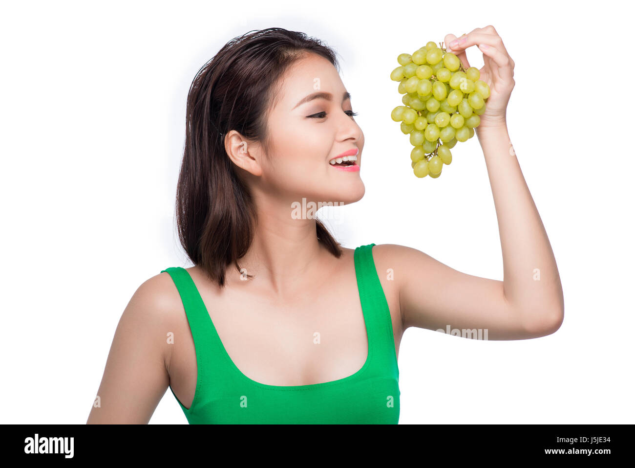 Giovane bella donna asiatica mangiare uva fresca isolati su sfondo bianco Foto Stock