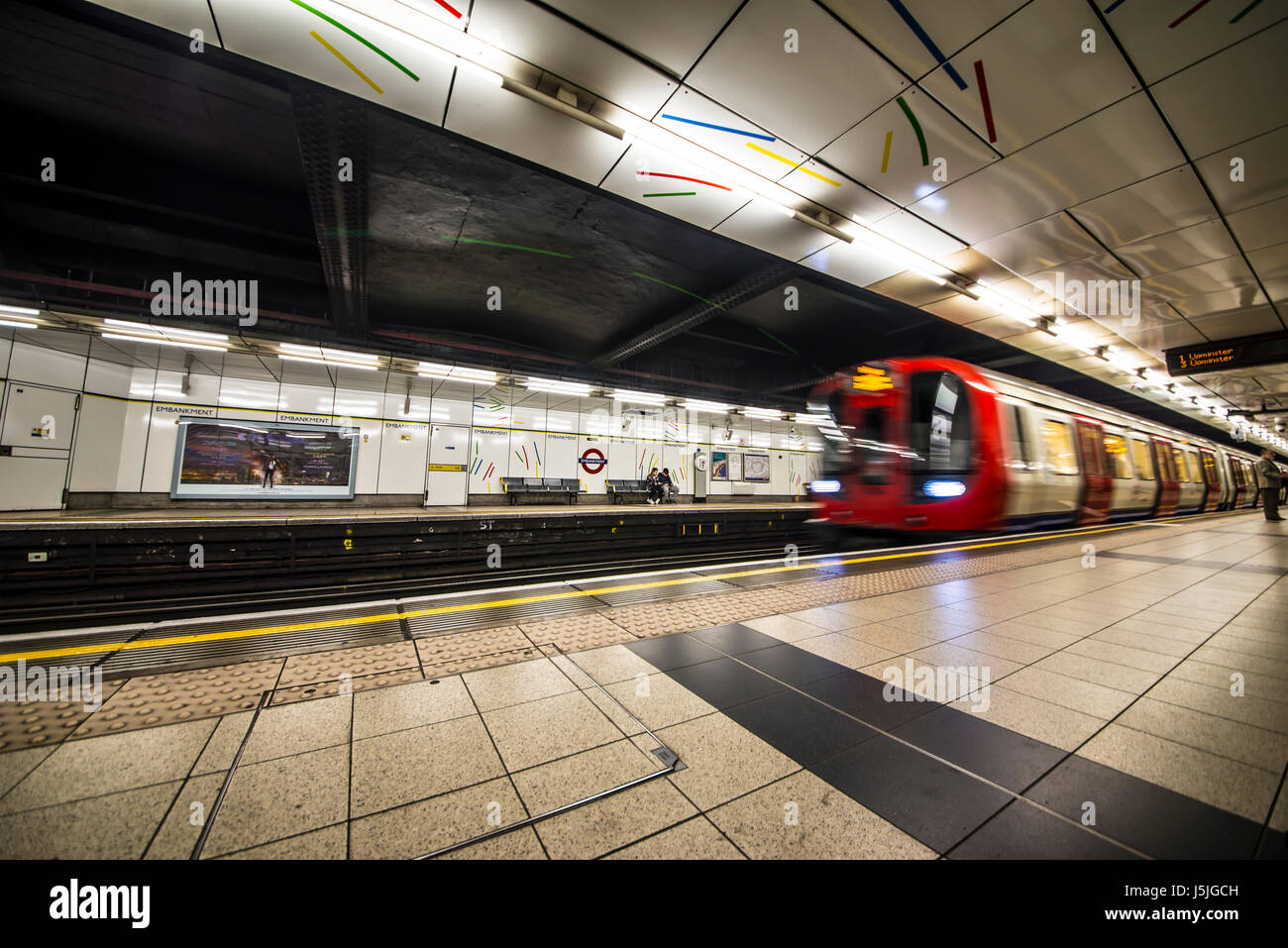 Stazione della metropolitana Embankment London con un treno che passa Foto Stock