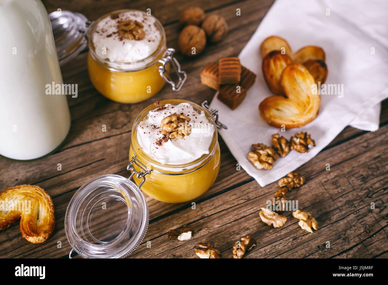 Frullato di zucca in un barattolo di vetro con la panna montata, caramella mou, noce e miele biscotti. Bottiglia di latte. Legno scuro dello sfondo. il fuoco selettivo. Foto Stock