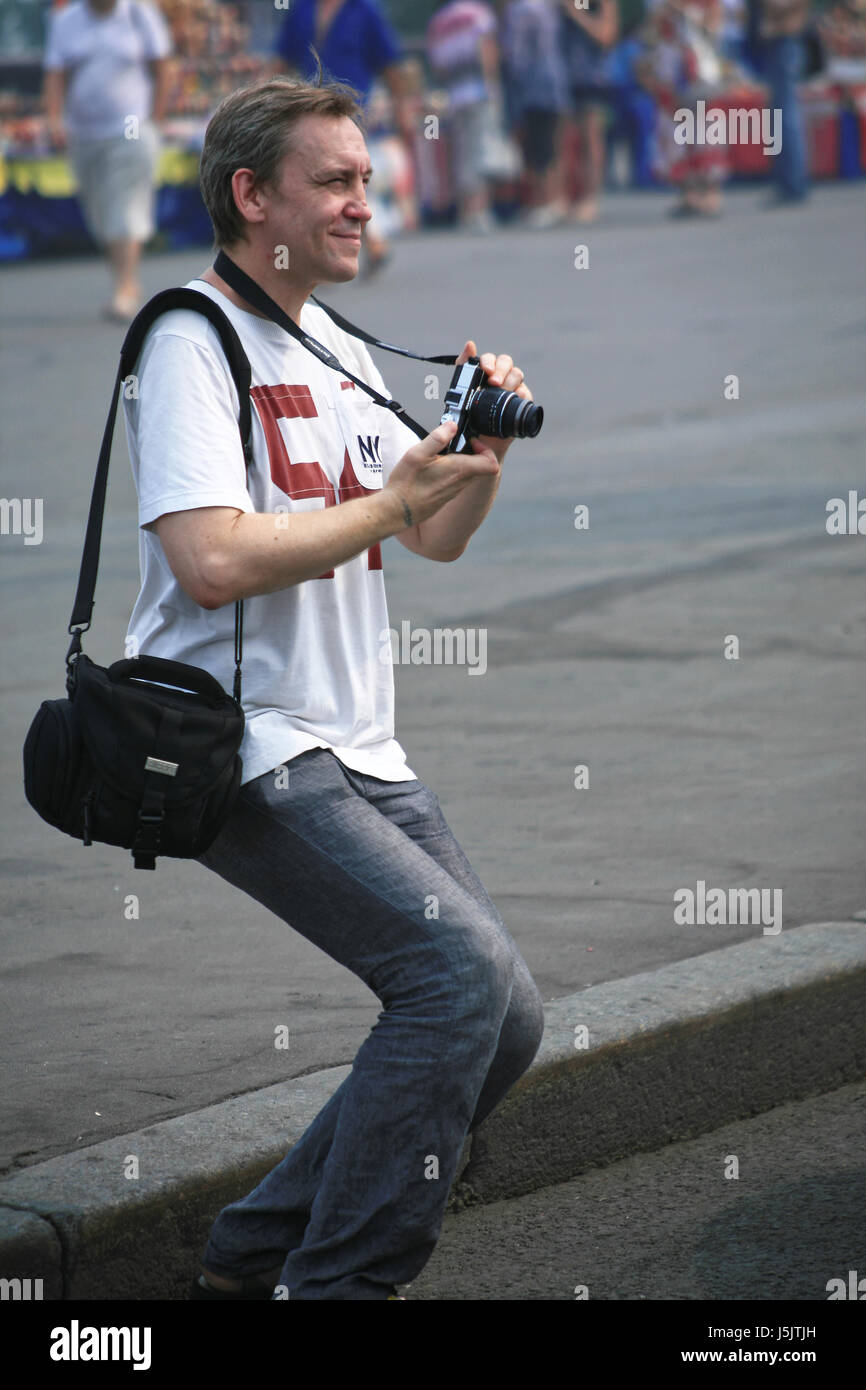 Il giovane uomo con una macchina fotografica in mano in una posa dinamica in strada Foto Stock