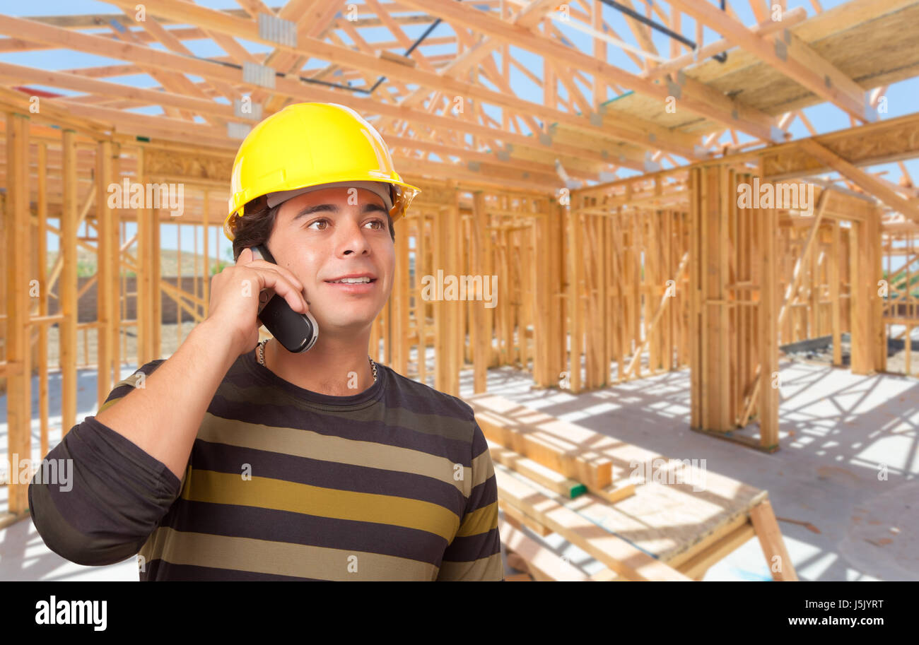 Contraente ispanica usando il telefono sul sito all'interno di nuova costruzione in casa Framing. Foto Stock
