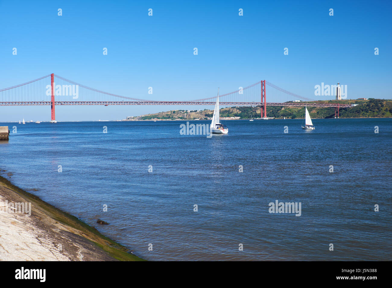 Xxv Aprile sospensione ponte ponte sul fiume Tago con Gesù Cristo Re statua sullo sfondo a Lisbona, Portogallo Foto Stock