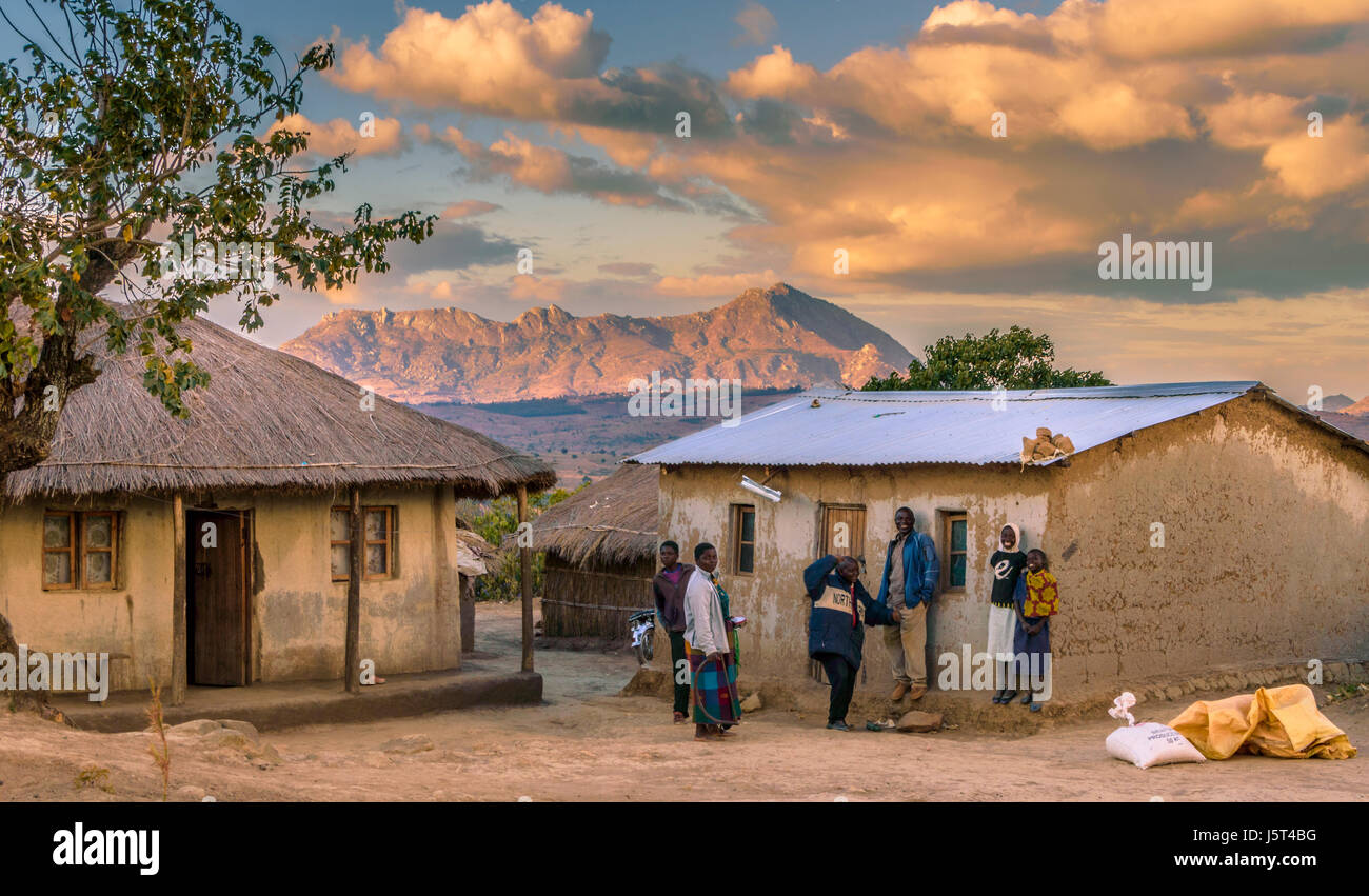 Tradizionale capanna di fango con tetto di erba a fianco di più moderno rifugio con ferro corrugato pacciamatura tetto in un villaggio rurale in Malawi, Africa Foto Stock