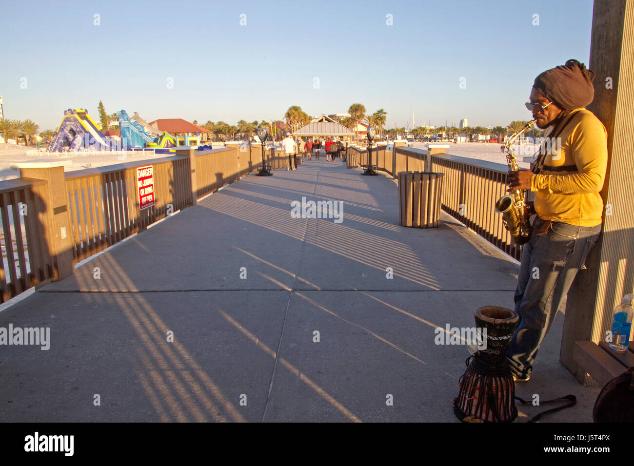 Clearwater Beach, Florida, Stati Uniti d'America - 24 Gennaio 2017: un suonatore ambulante suona il sassofono per suggerimenti come persone stoll intorno al tramonto al Molo 60 in Clearwater essere Foto Stock