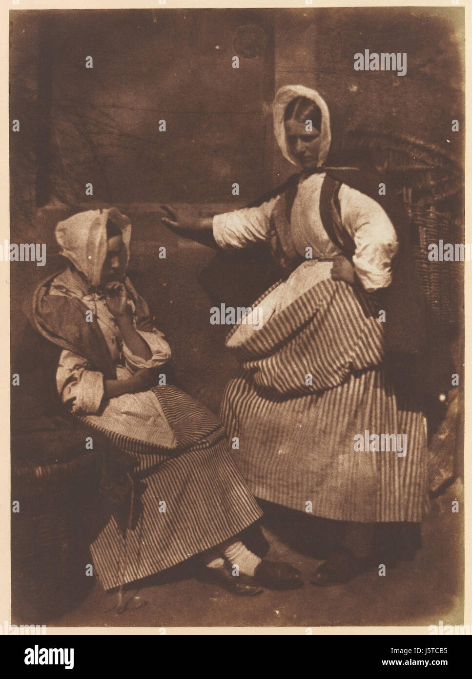 "Newhaven Fishwives" è un dipinto che raffigura la vita quotidiana delle donne nella città costiera di Newhaven, in Inghilterra. L'opera d'arte ritrae le pescivie, donne che tradizionalmente vendevano pesce ai mercati, trasportando cesti pieni di pesce. Il dipinto cattura la vitalità e il lavoro della comunità locale, offrendo uno sguardo sullo stile di vita della classe operaia di Newhaven alla fine del XIX secolo. Foto Stock