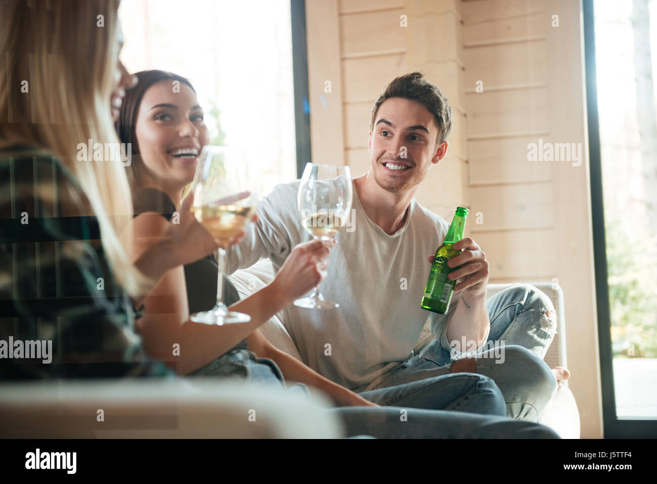 Il gruppo di allegro giovani amici di bere il vino e la birra sul divano di casa Foto Stock