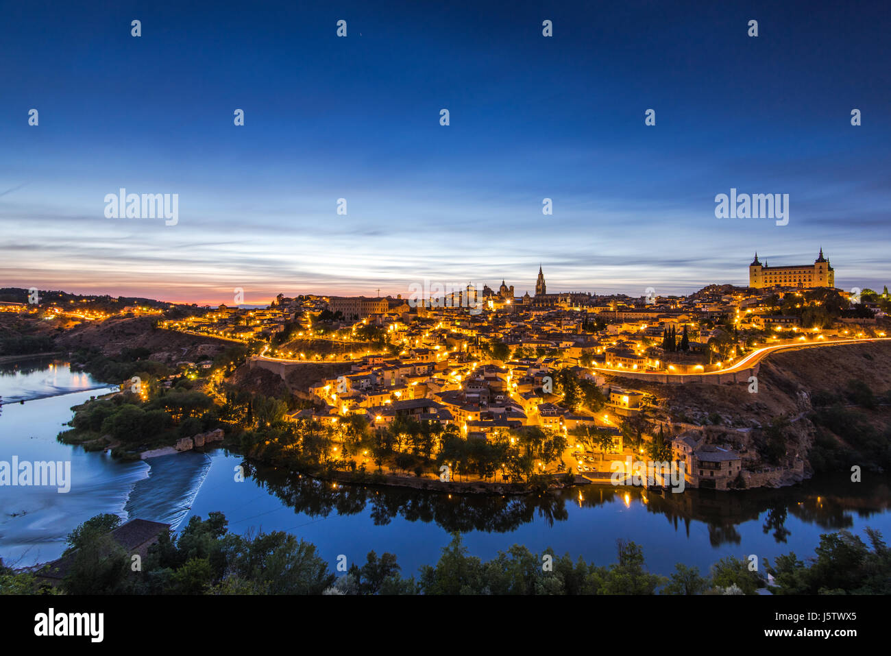 Paesaggio notturno illuminato di Toledo in Spagna e tranquillo fiume Tago a valle. Foto Stock