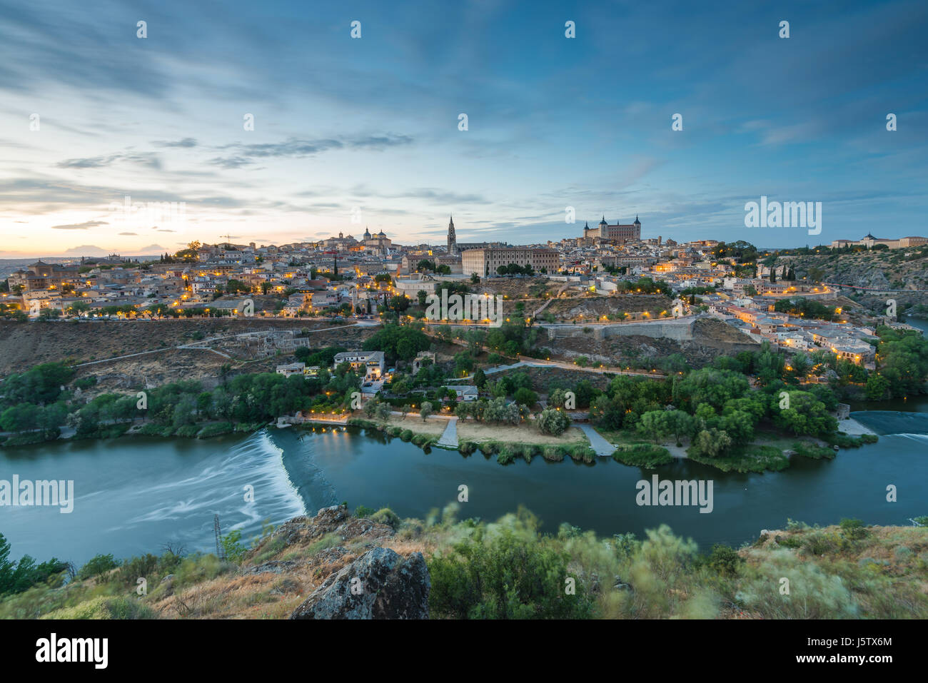 Ponoramic cityscape di Toledo in Spagna con illuminazione di strade e il fiume Tangus in valle. Foto Stock