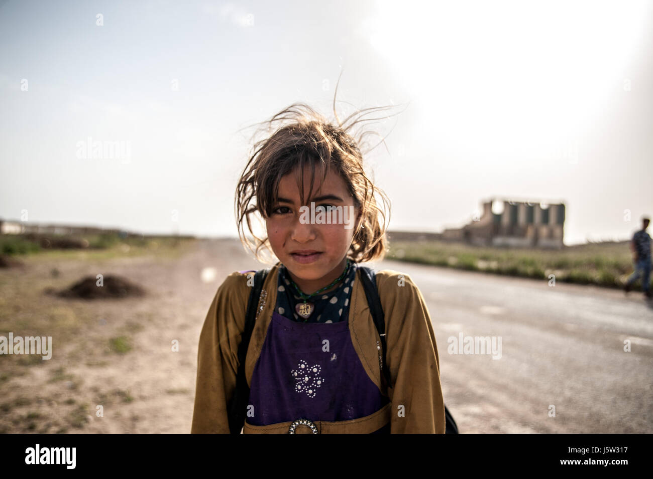 Un internamente sfollati ragazza sta al di fuori di Hammam Alil al camp in prossimità degli edifici rovinato da uno Stato islamico Foto Stock