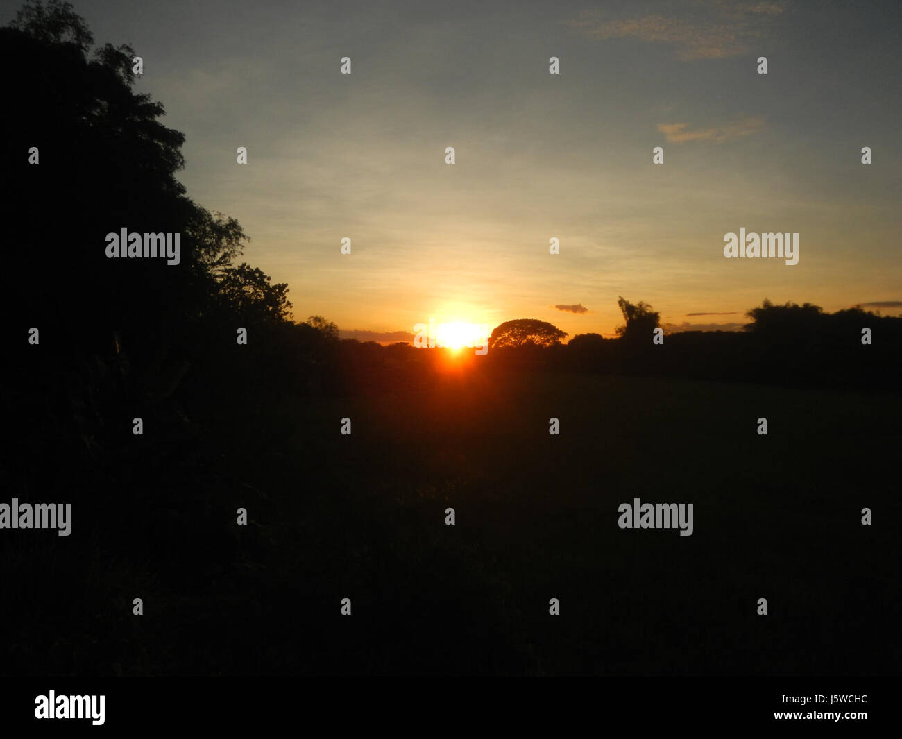 Questa immagine cattura le vibranti vedute del tramonto a Galas, Maasim, San Rafael, Bulacan, Filippine. Conosciuta per i suoi paesaggi panoramici, questa zona rurale offre splendide vedute del tramonto sui campi e sulle colline circostanti. Foto Stock