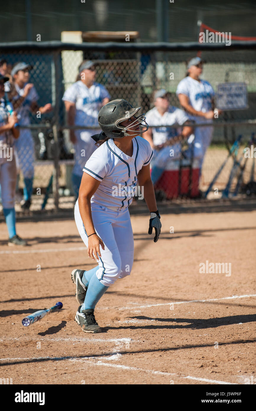 Latina softball player osservando il suo hit volare come gocce di bat. Foto Stock