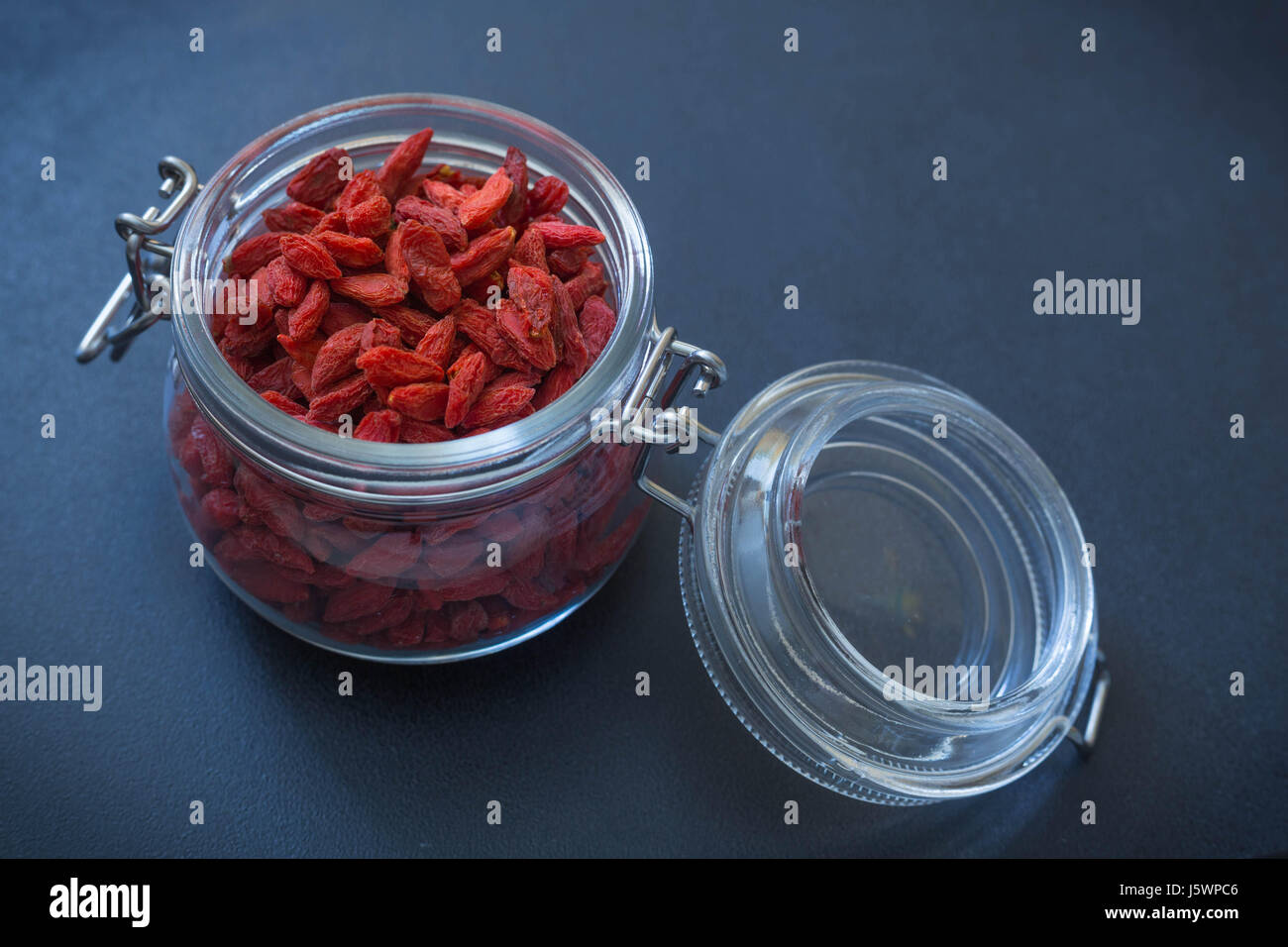 Essiccato a bacca Goji in un vaso in pietra scura sullo sfondo Foto Stock