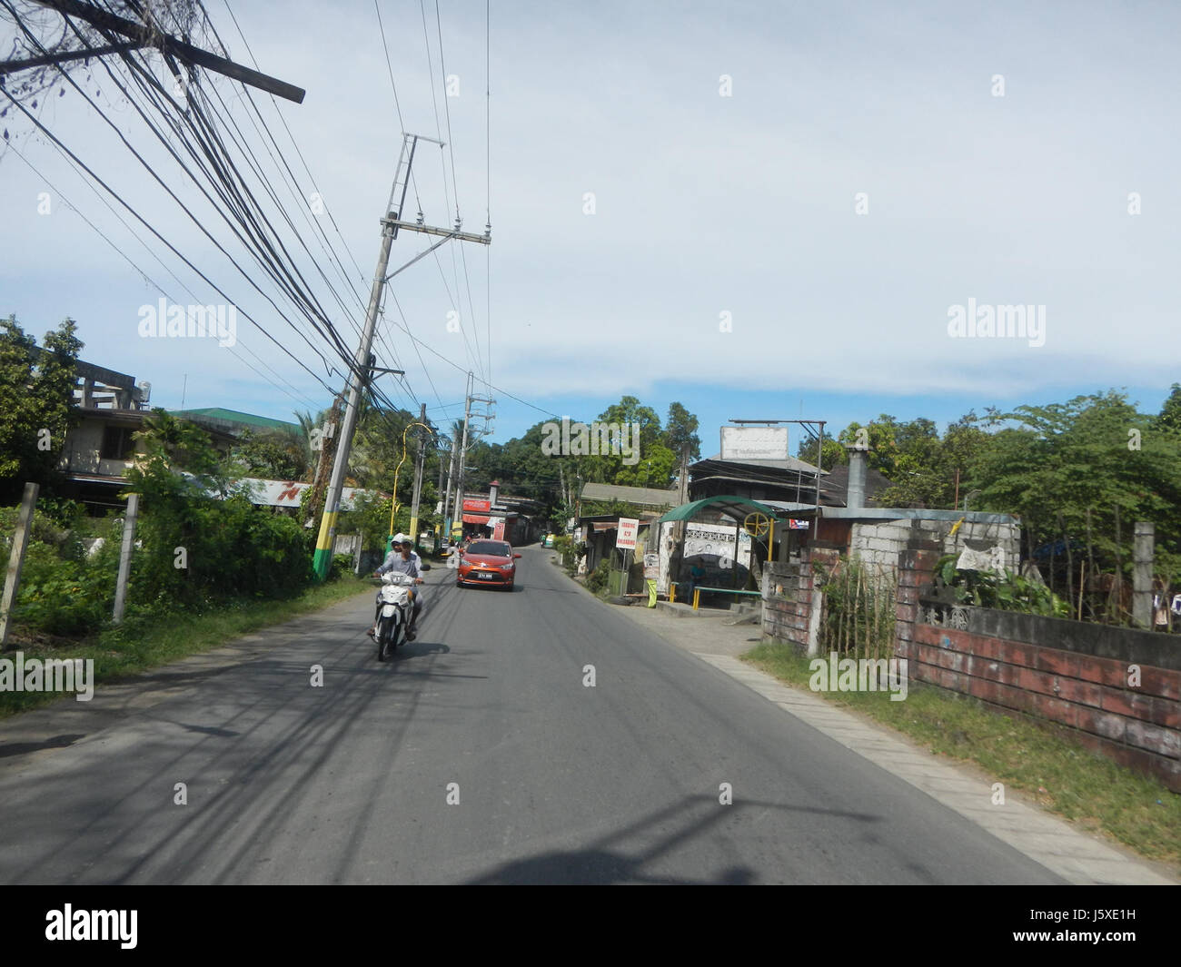 Questa immagine mostra le attività di costruzione lungo una strada nelle aree di Poblacion San Roque e Bagong Barrio di Pandi, Bulacan, Filippine. La scena evidenzia lo sviluppo delle infrastrutture in un'area suburbana. Foto Stock