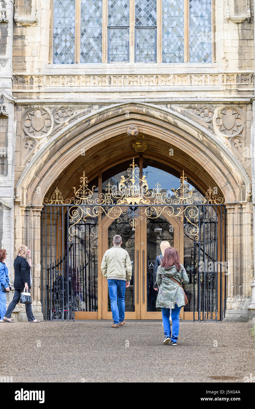 I visitatori entrano dalla porta principale alla facciata ovest della medievale cattedrale cristiana a Peterborough, Inghilterra. Foto Stock