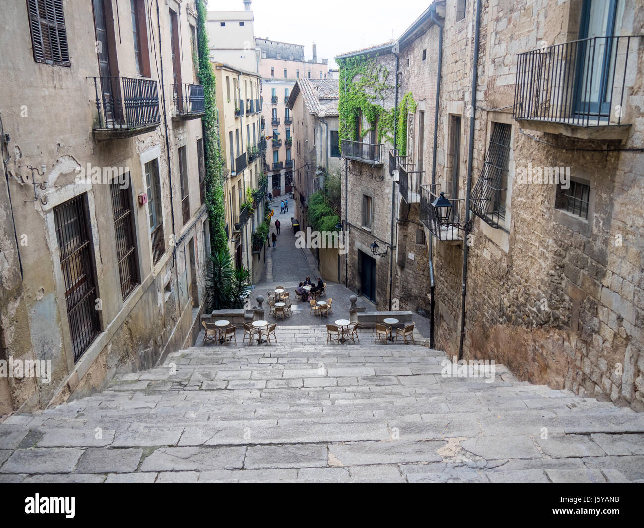 Guardando in giù per le scale di Pujada de Sant Domènec a tavoli e sedie per pranzare al fresco nella città di Girona, Spagna. Foto Stock