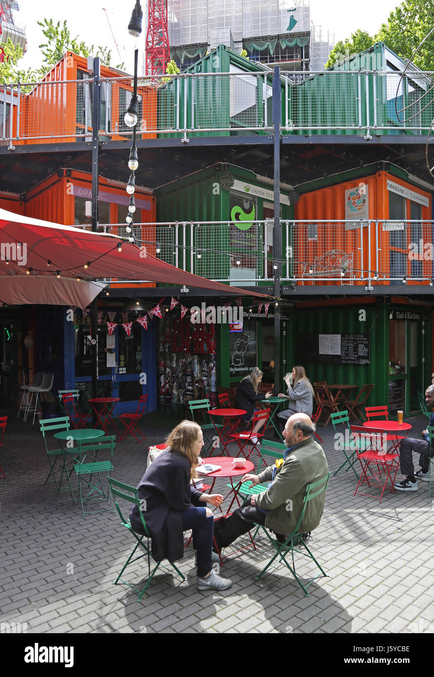 Un paio di sedersi a un Cafè presso le opere di elefante, uno sviluppo di uffici negozi e caffetterie nel sud di Londra costruita da contenitori di spedizione. Foto Stock