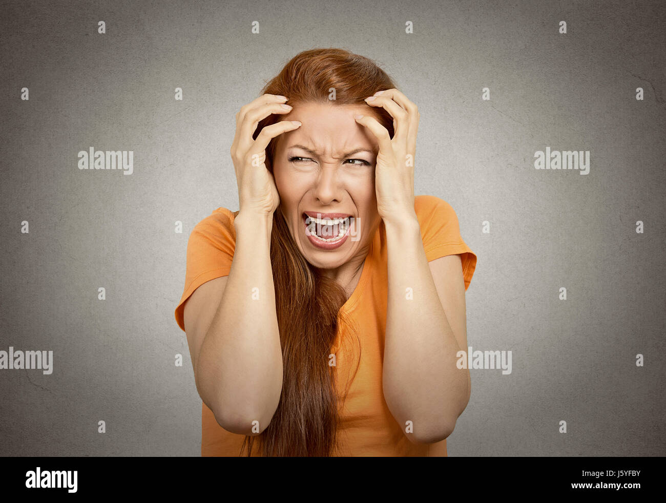 Closeup ritratto sottolineato sconvolto donna avente ripartizione urlare isterica urlando temper tantrum isolato sfondo arancione. Negativo emozione umana Foto Stock
