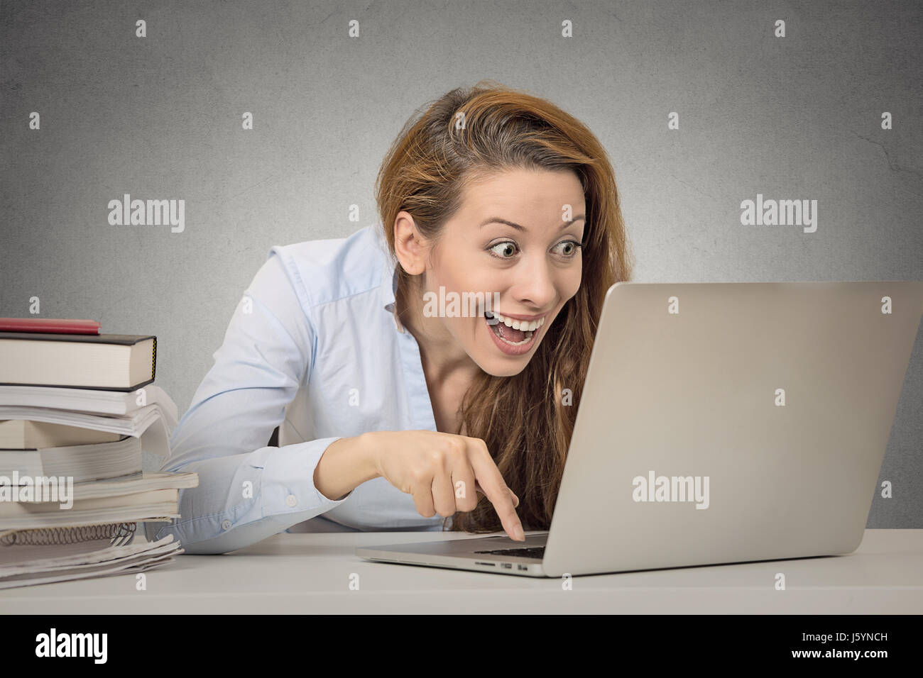 Donna al lavoro su computer pronto premere il pulsante invio isolato ufficio grigio Sfondo a parete. Funny funky pazzo cercando girl eccitato ciò che vedi sul computer portatile Foto Stock