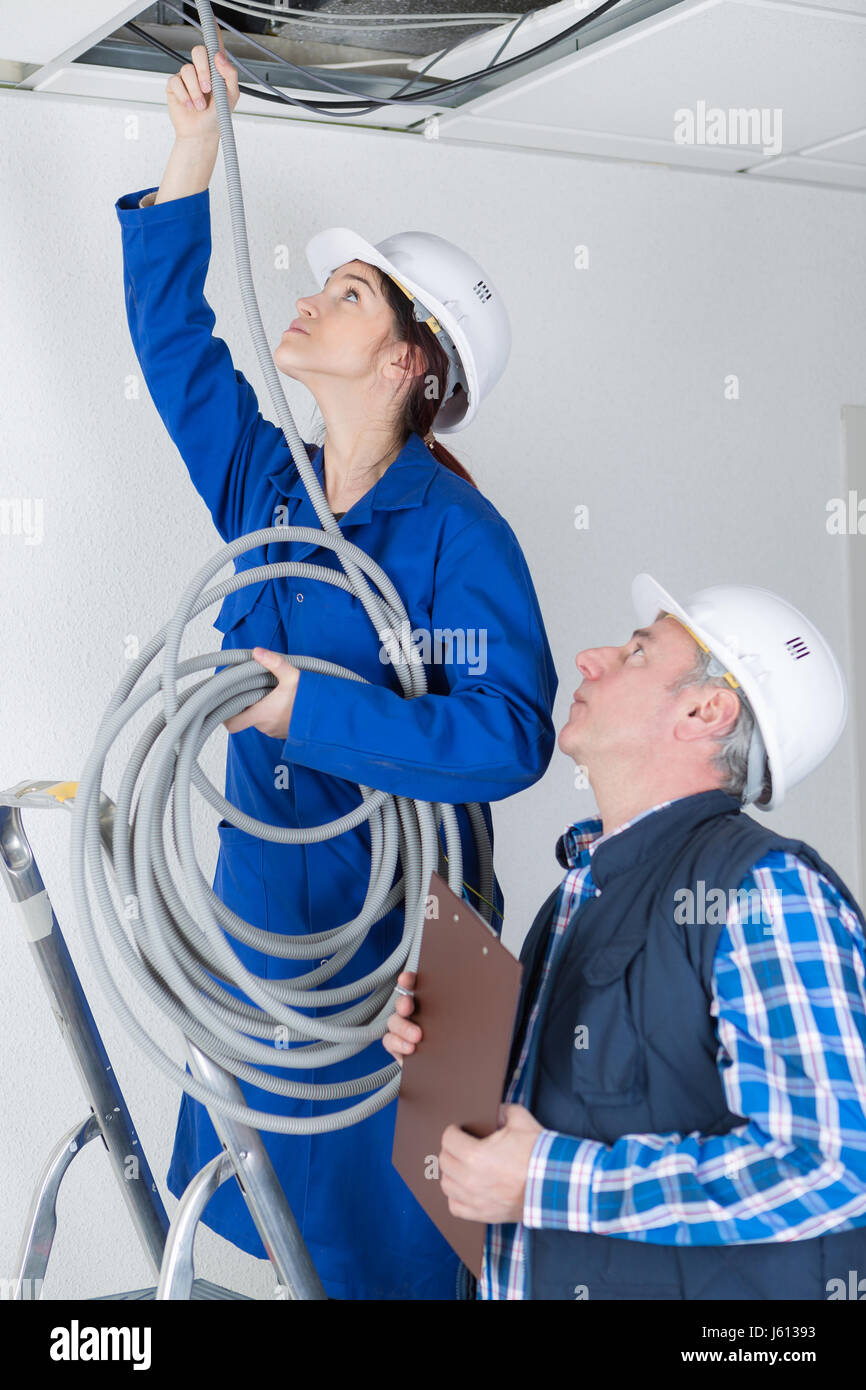 Donna cavo di alimentazione sopra il soffitto sospeso Foto Stock