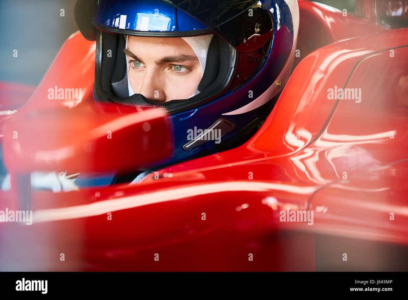 Close up focalizzata pilota di Formula Uno che indossa il casco in macchina da corsa Foto Stock