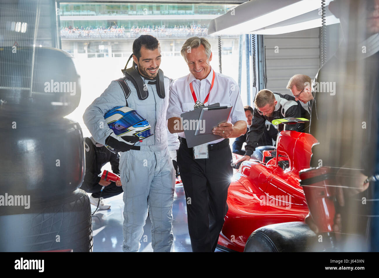 Manager e gara di Formula Uno auto conducente parlando nel garage di riparazione Foto Stock