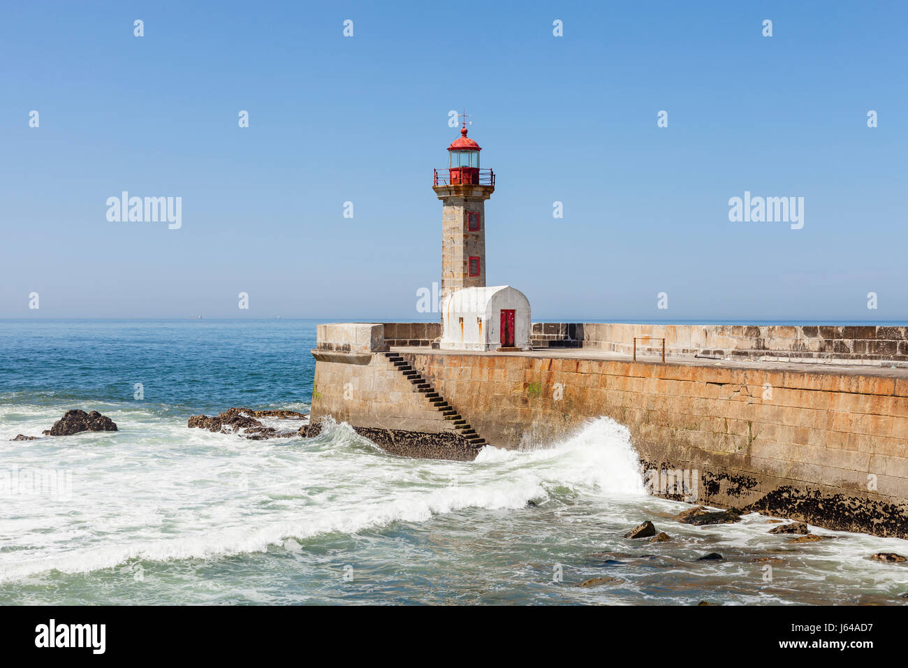 Porto, Portogallo - Le onde si infrangono contro la Felgueiras Faro e frangiflutti in Foz do Douro Foto Stock