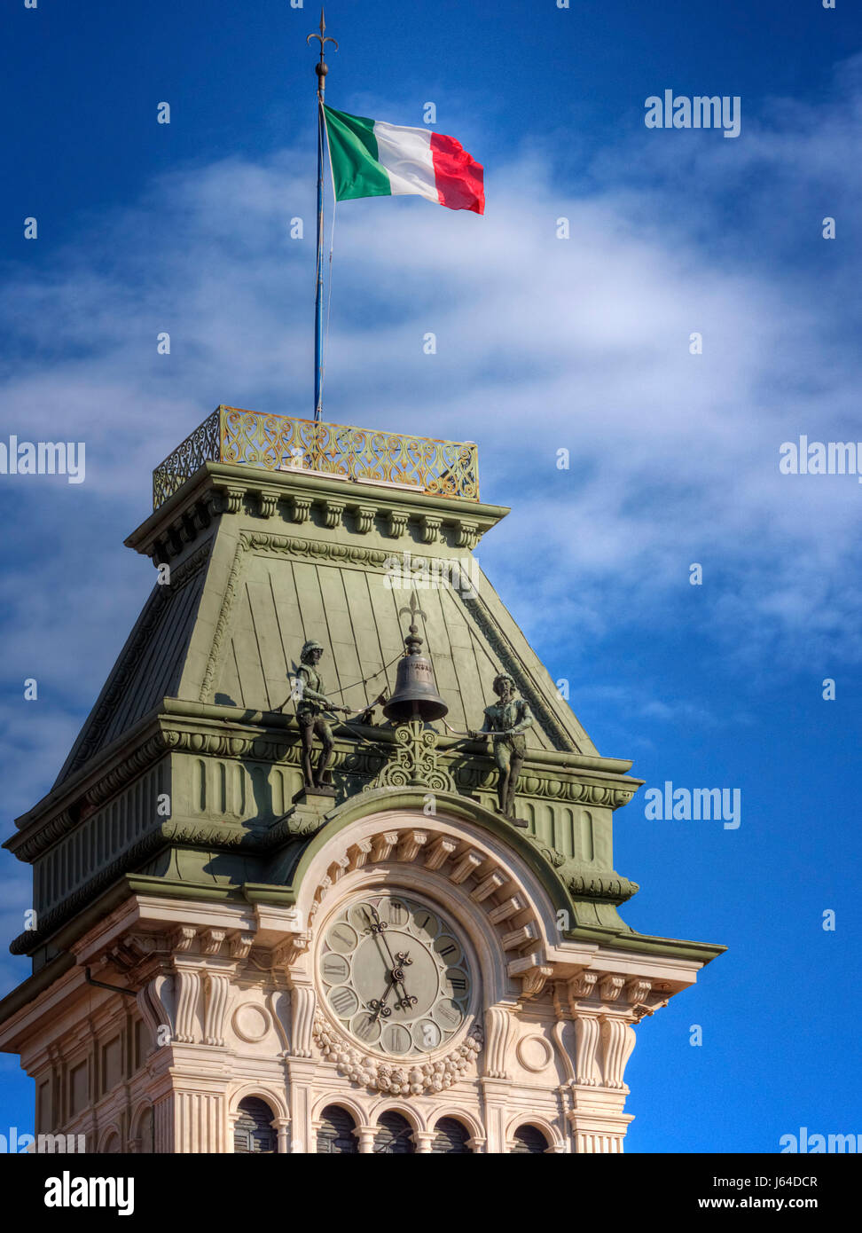 L'orologio e il campanile a torre di Trieste con la bandiera italiana sulla parte superiore. Foto Stock