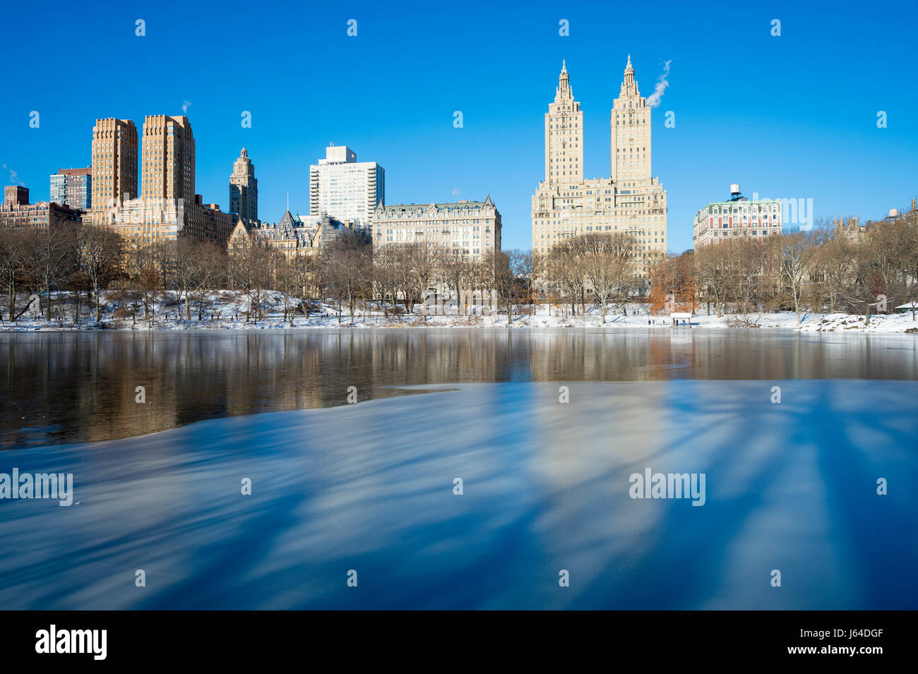 Vista panoramica della Upper West Side skyline riflettendo nel ghiaccio della congelata di Central Park Lake la mattina dopo un New York City inverno tempesta di neve Foto Stock