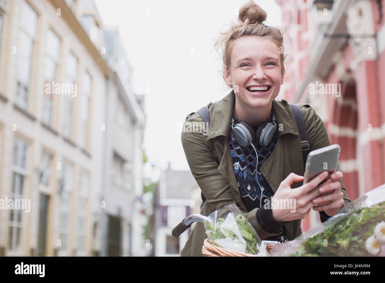 Ritratto entusiasta giovane donna sulla bicicletta texting sulla strada di città Foto Stock