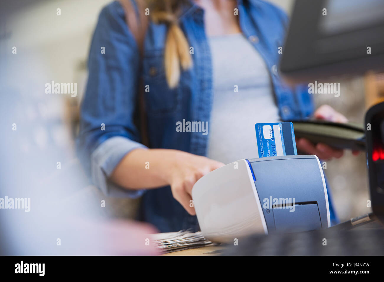 Shopper femmina usando un lettore di carte di credito in negozio Foto Stock