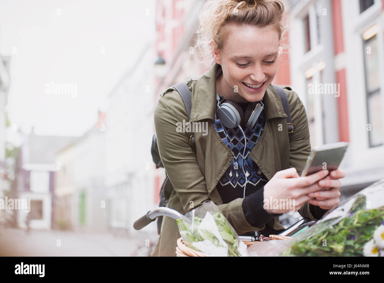 Sorridente giovane donna texting con un telefono cellulare in bicicletta sulla strada di città Foto Stock