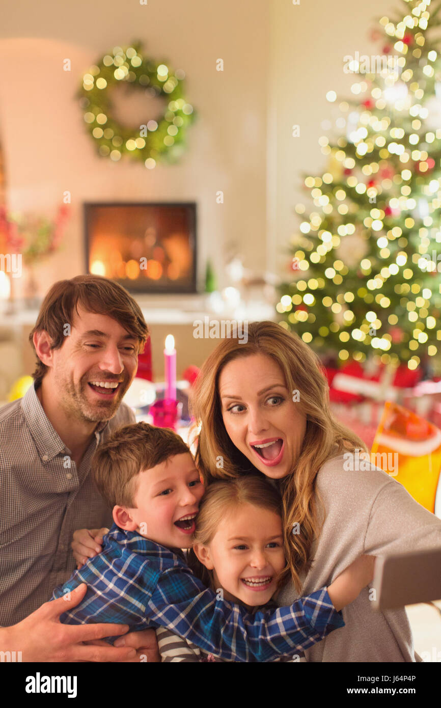 Silly famiglia selfie prendendo con la fotocamera del telefono in Natale soggiorno Foto Stock