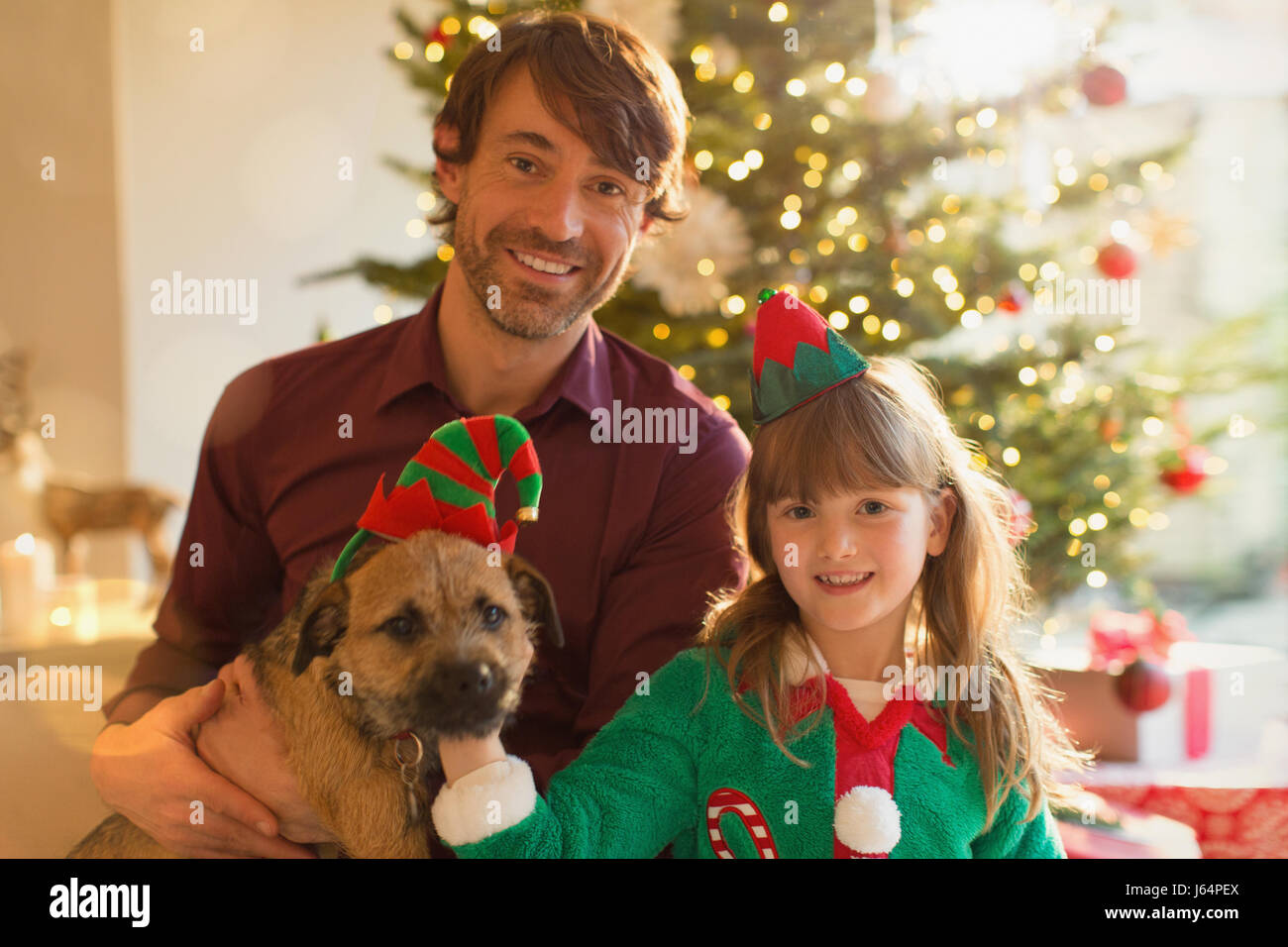 Ritratto sorridente padre, la figlia e il cane nella parte anteriore dell albero di Natale Foto Stock
