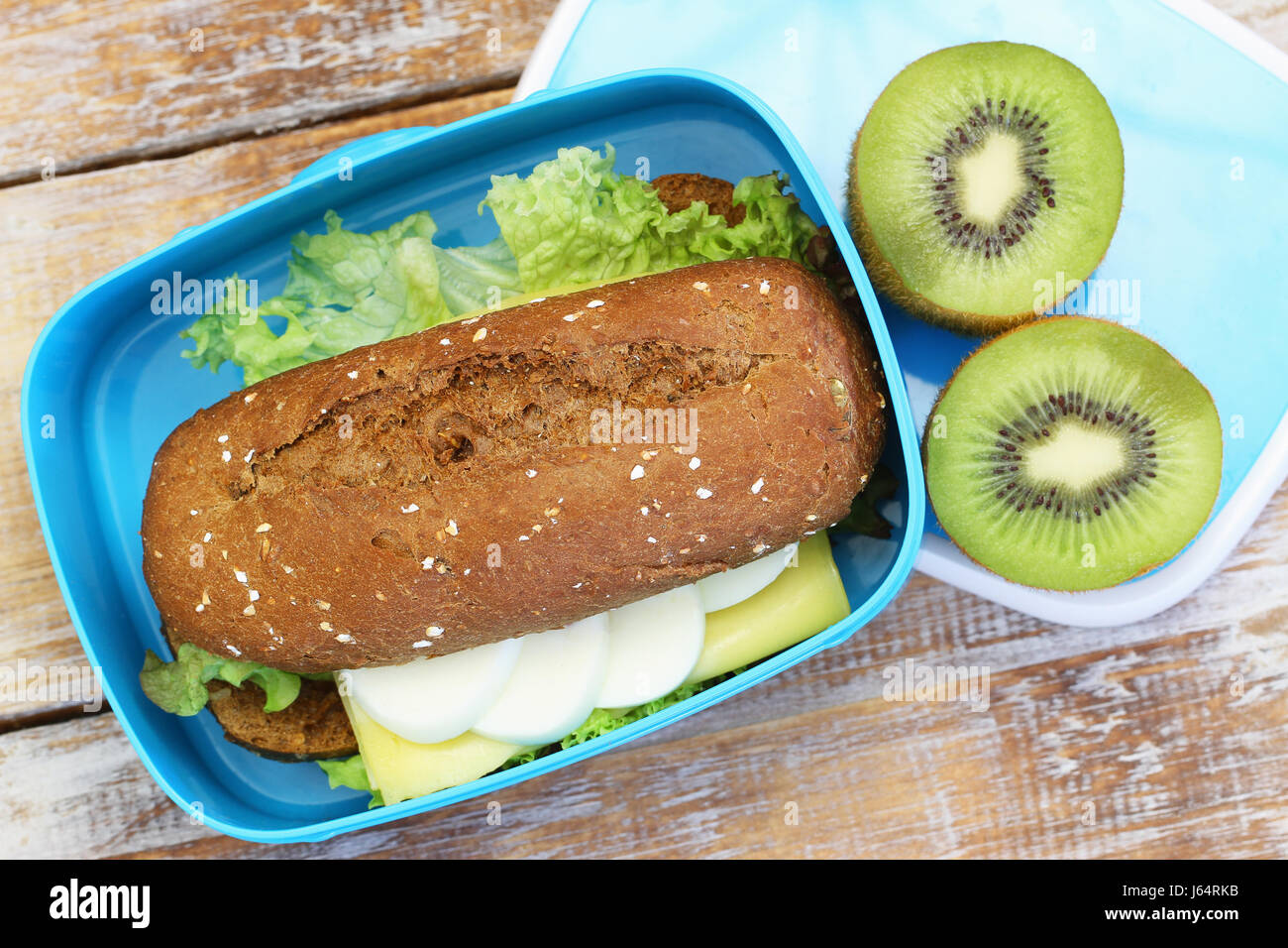 Un sano pranzo al sacco contenente il rullo di marrone con formaggio e uovo sodo e kiwi Foto Stock