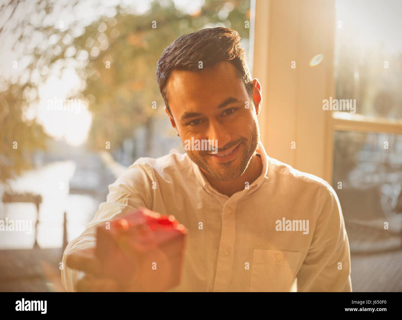 Punto di vista personale giovane dando dono nella soleggiata cafe Foto Stock