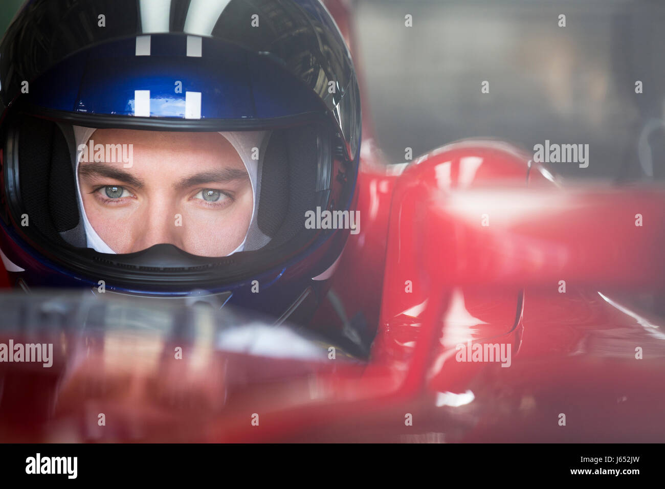 Close up focalizzata gara di Formula Uno pilota di auto nel casco che guarda lontano Foto Stock