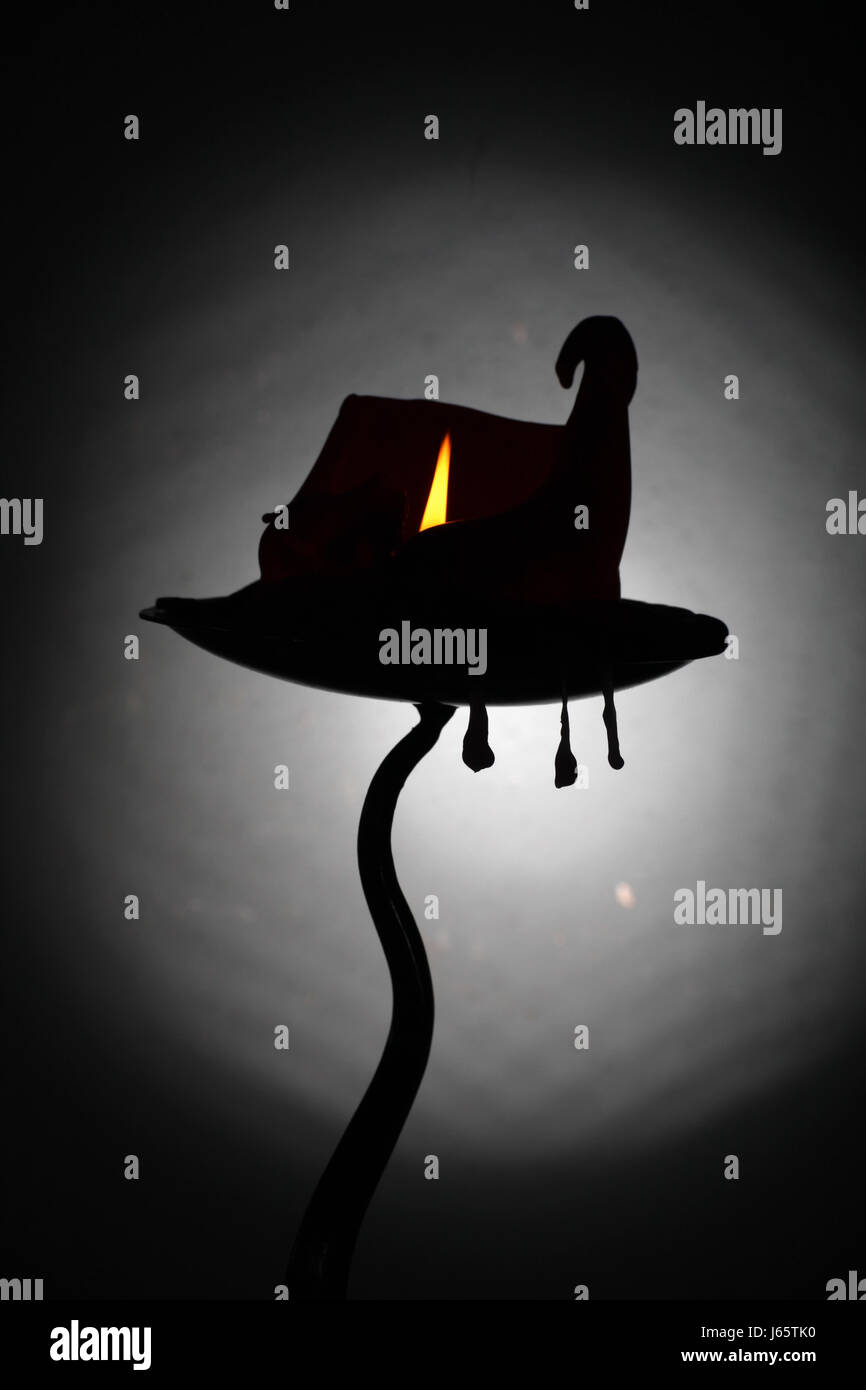Un nodose curling candela che brucia che assomiglia a una streghe hat / Haunted House , con tre pendente in cera cola sospesi da portacandele. Foto Stock