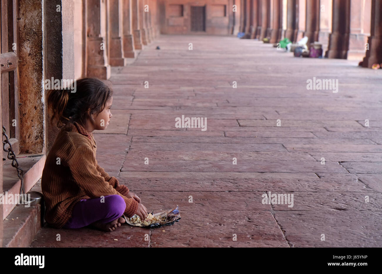 Una ragazza povera di mangiare in Fatehpur Sikri complessa, Uttar Pradesh, in India nel febbraio, 15, 2016. Foto Stock