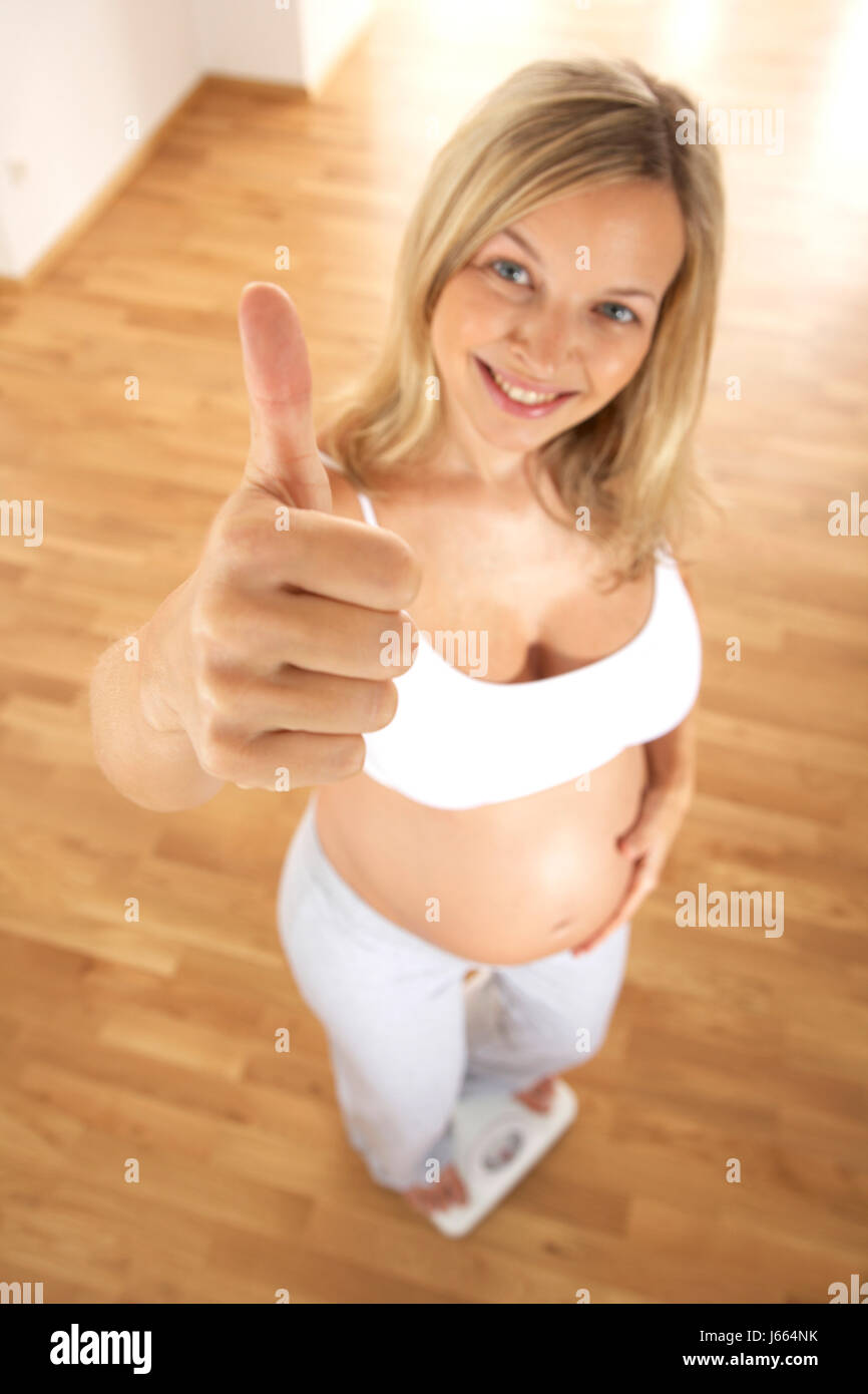 Donna incinta in piedi sulla bilancia da bagno Foto Stock