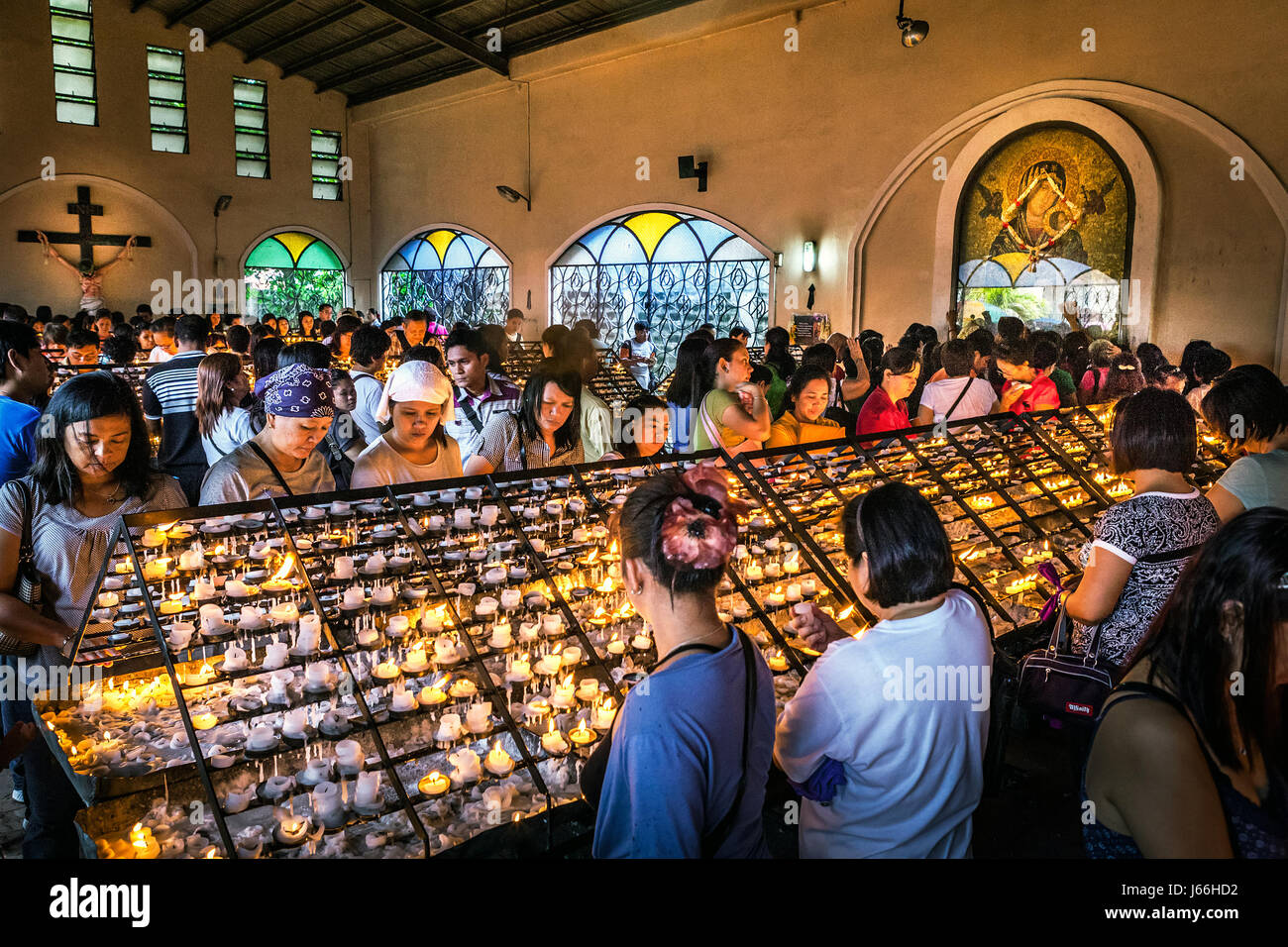 I devoti Cattolici luce di candele votive nella chiesa redentorista a Manila nelle Filippine. Foto Stock
