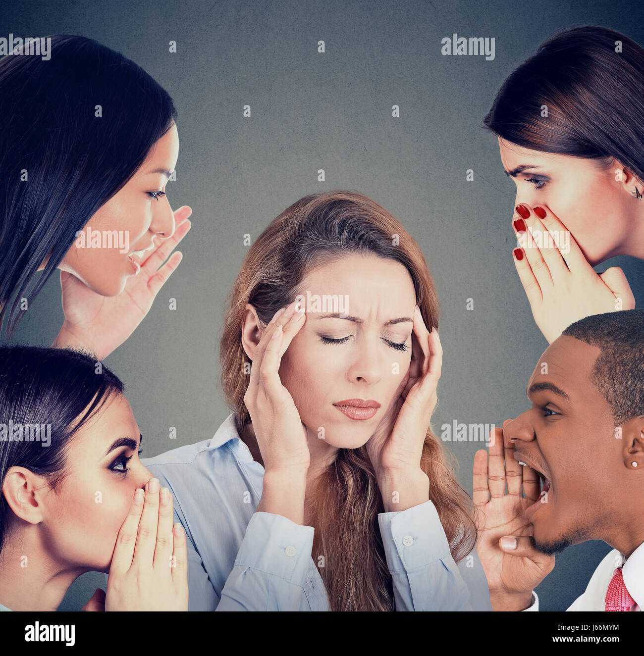 Un gruppo di giovani whispering gossip per una donna ha sottolineato che soffrono di mal di testa Foto Stock