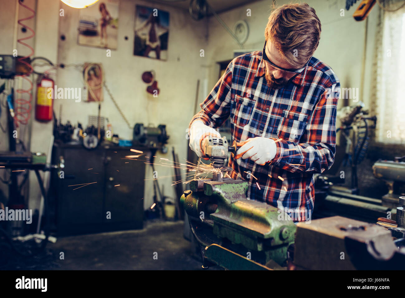 Giovane lavoratore manuale lavora con la fresa Foto Stock