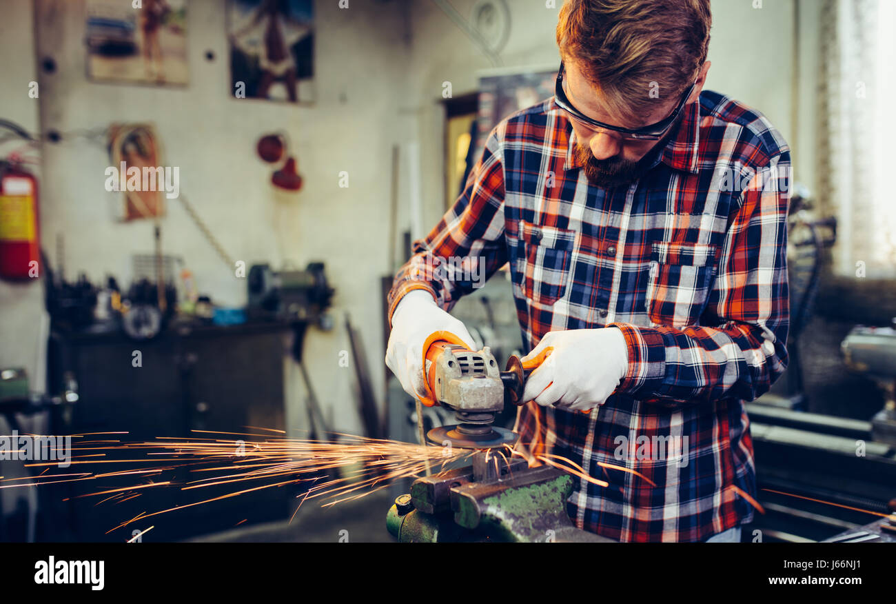 Giovane lavoratore manuale lavora con la fresa Foto Stock