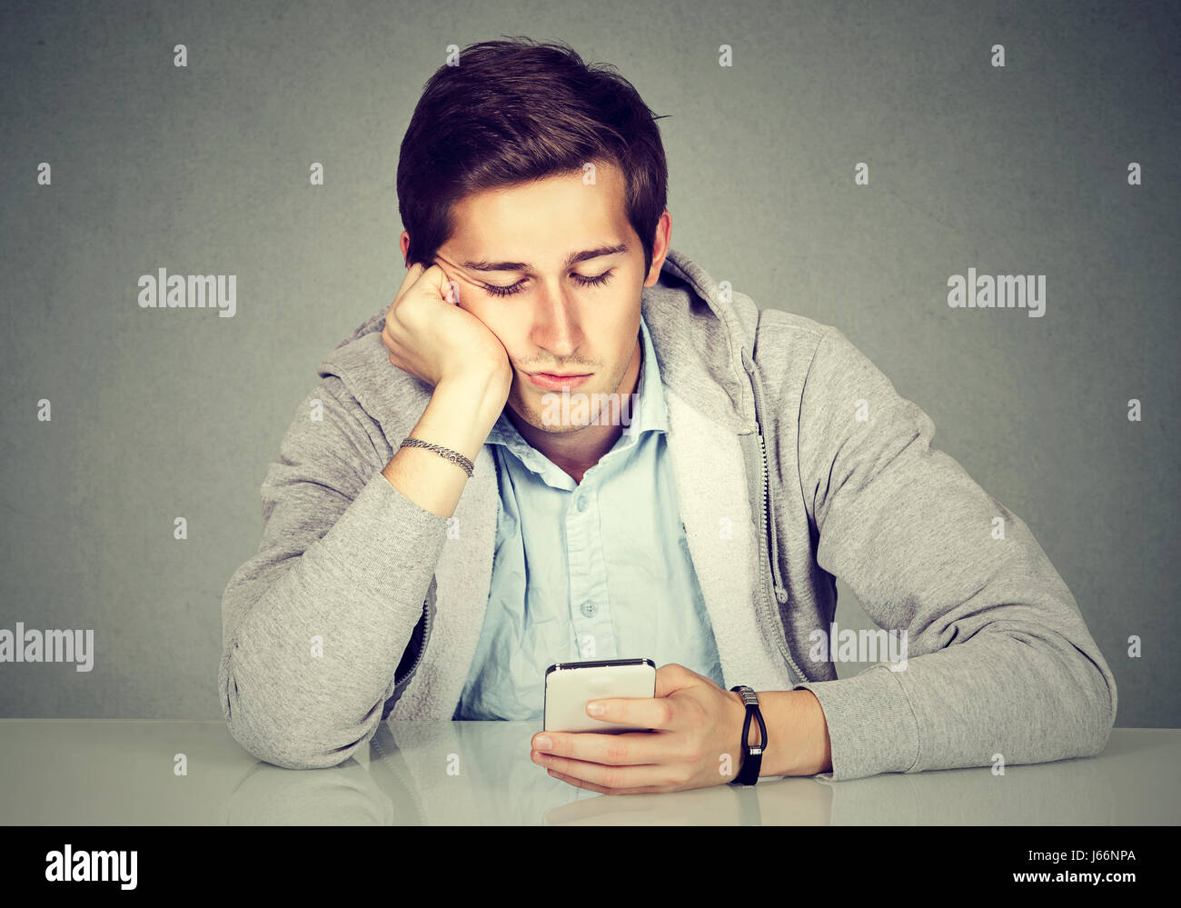 Annoiarsi l uomo con il suo smart phone Foto Stock