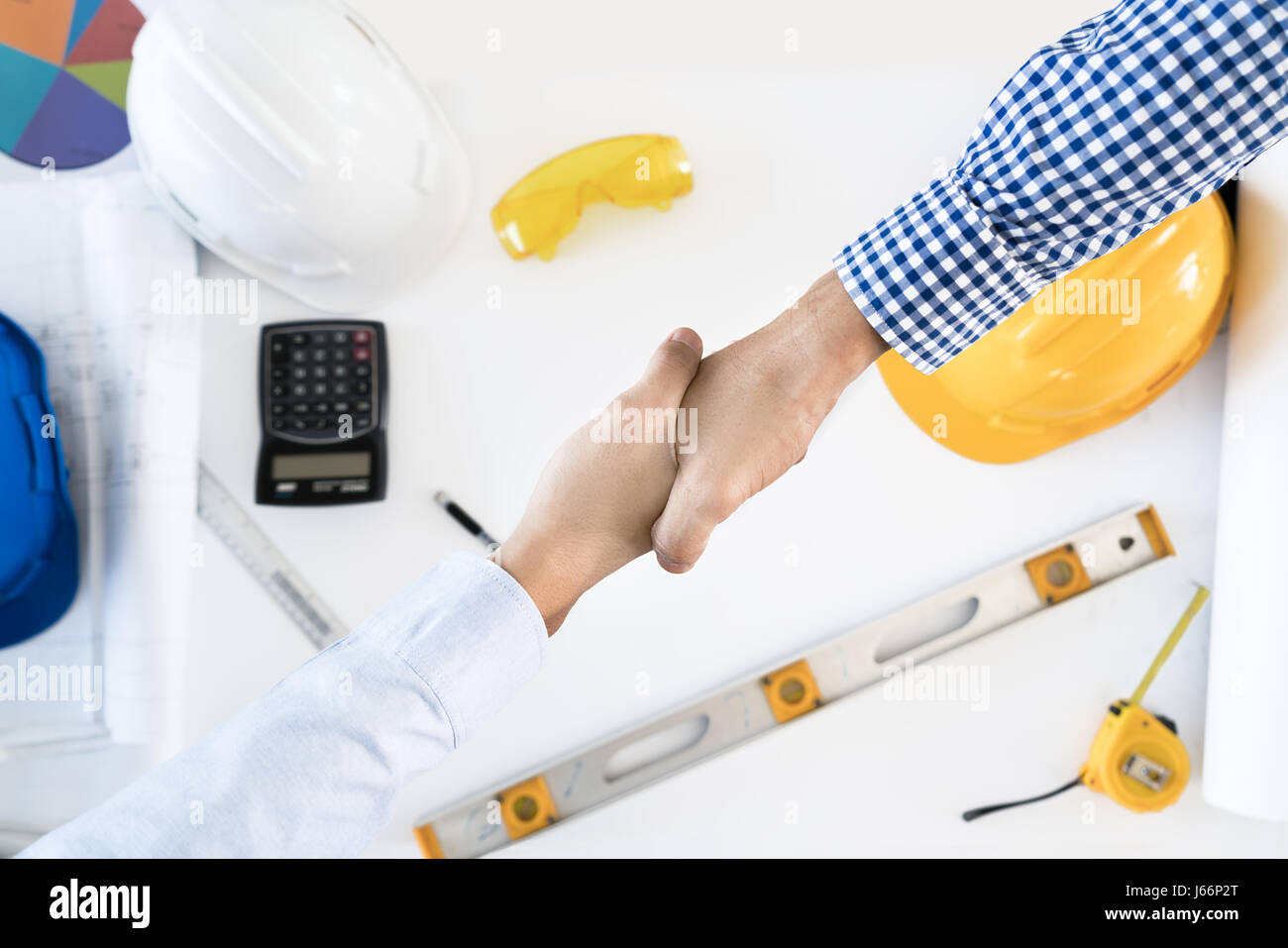 Vista superiore architetto e ingegnere stringono le mani, la finitura di una riunione sul progetto di costruzione e strumenti. Agitando mani il concetto di accordo. Foto Stock
