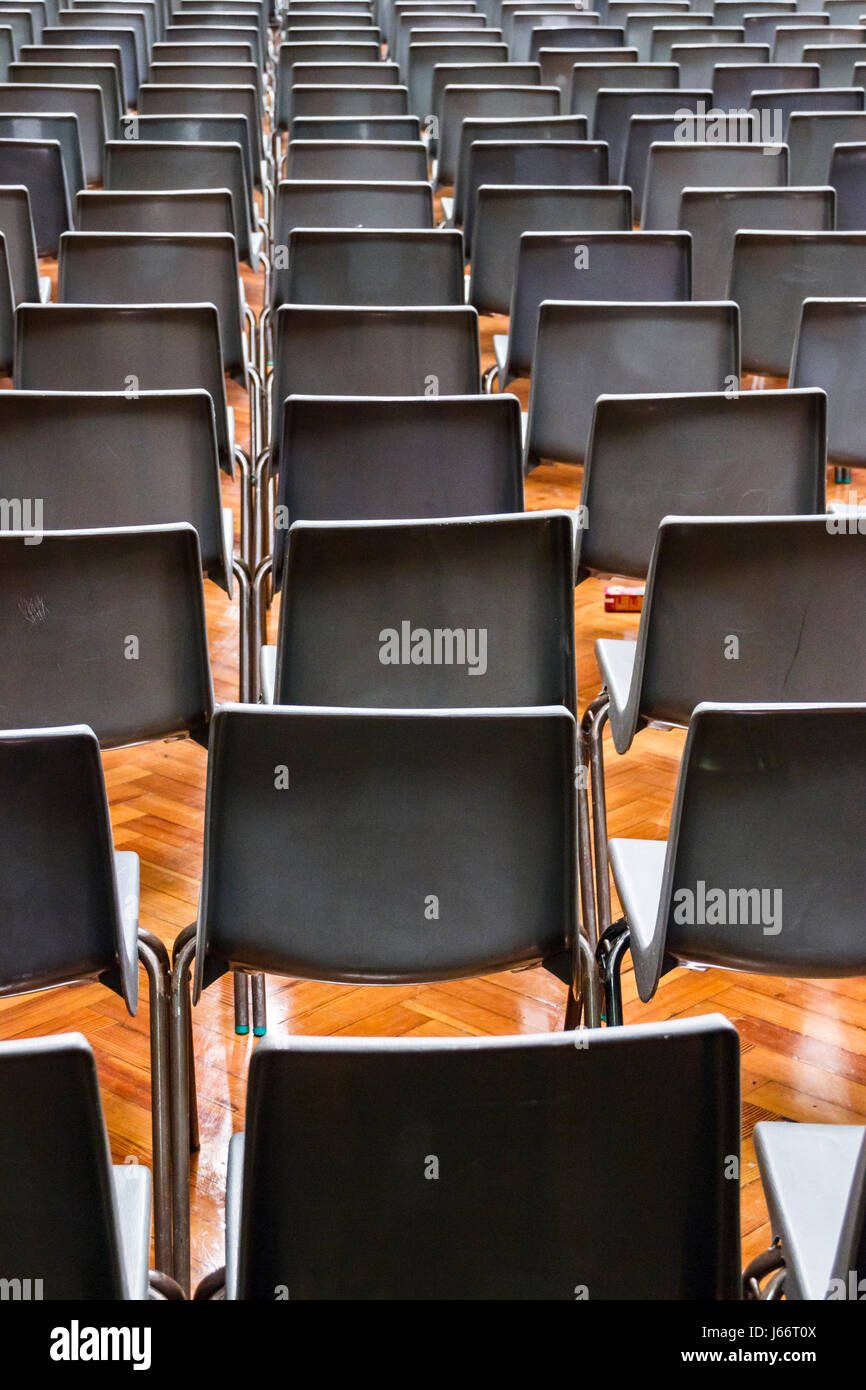 Grigio sedie di plastica disposti in righe per un concerto o una presentazione in una sala vuota o auditorium Foto Stock