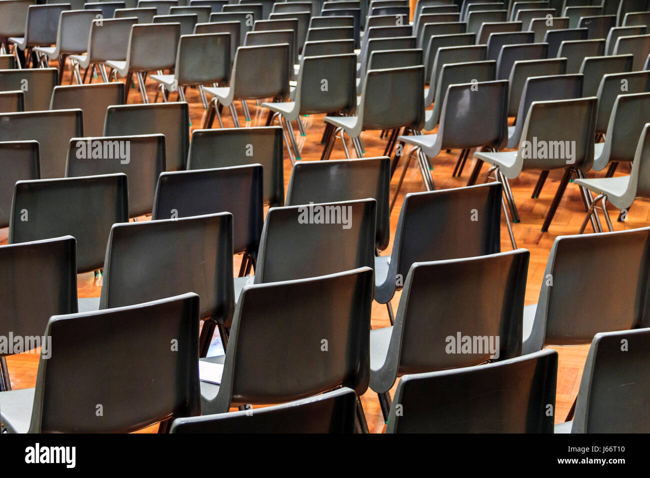 Grigio sedie di plastica disposti in righe per un concerto o una presentazione in una sala vuota o auditorium Foto Stock